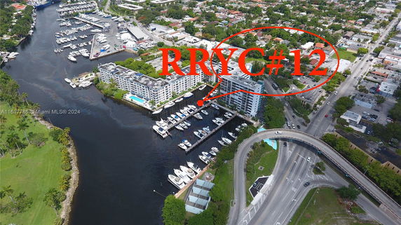 Panoramic view of a waterfront building complex with a marina and surrounding cityscape.