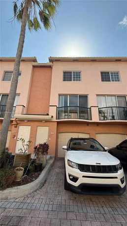 Front view of a multi-story residential building with garages and balconies.