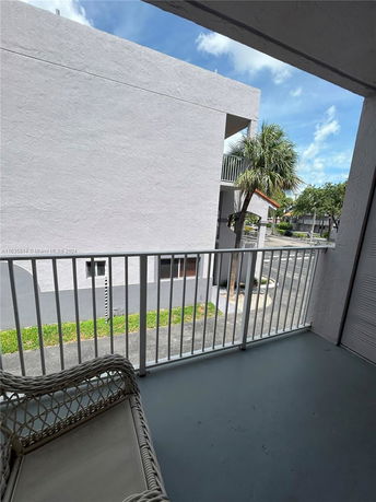 View from a balcony overlooking a building and a tree.