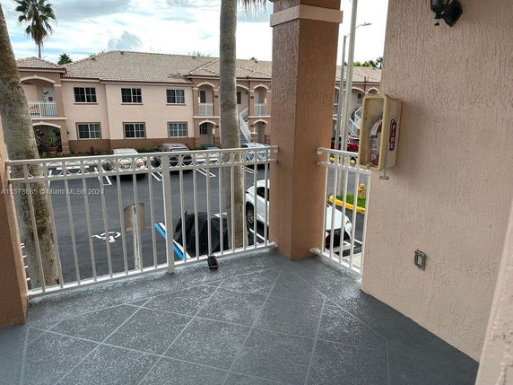 View of a parking area adjacent to a beige two-story building.