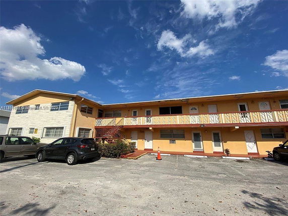 Front view of a two-story apartment building with parking space.