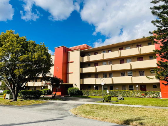 Front view of a multi-story residential building with balconies and a red vertical accent.