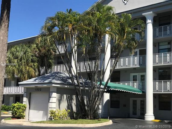 Front view of a multi-story residential building with balconies and a covered entrance.