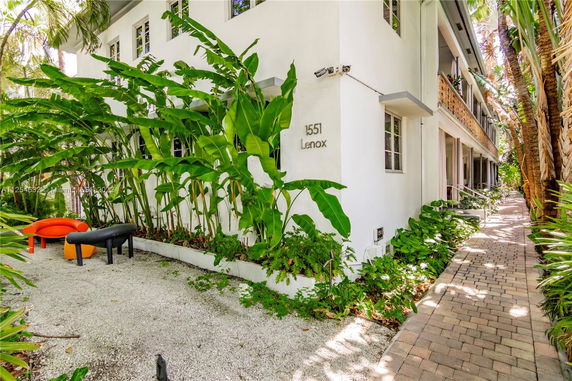 Front view of a two-story building with tropical plants.