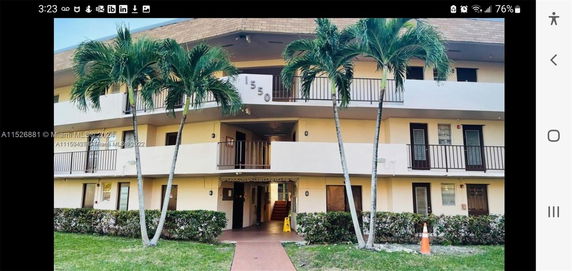Front view of a multi-story building with balconies and palm trees.