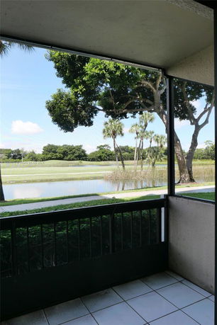View of a lake and trees seen from a covered balcony or patio.