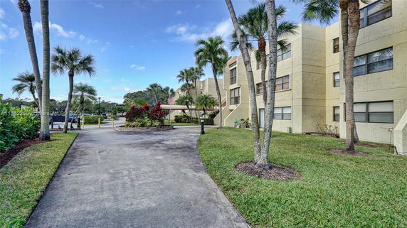 Front view of a multi-story building with a landscaped driveway.