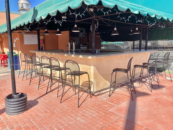 Outdoor bar area with stools and a canopy.