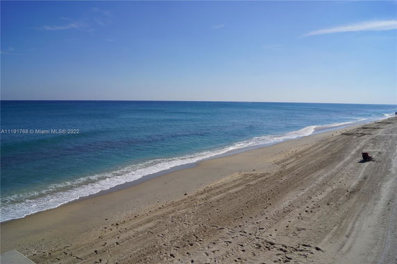 Panoramic view of a beach with clear blue water and sand.