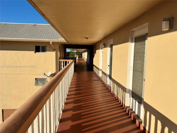 Exterior corridor of an apartment building with a view of adjacent rooftops.