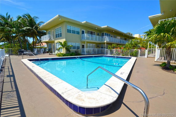 Outdoor view of a swimming pool with apartment buildings in the background.