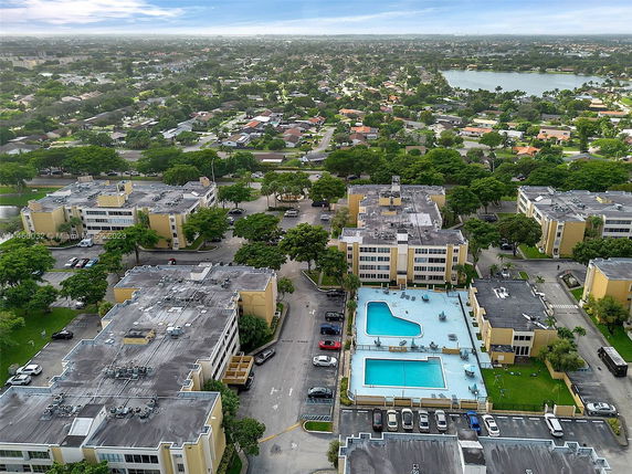 Aerial view of a residential area with multiple buildings, parking spaces, and a swimming pool.