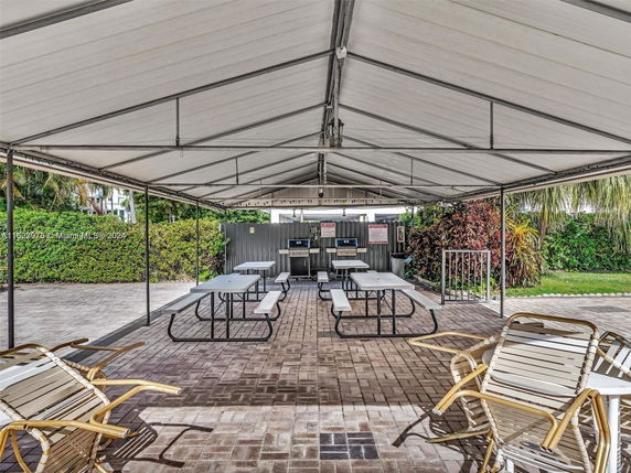 Outdoor picnic area with tables and chairs under a canopy.