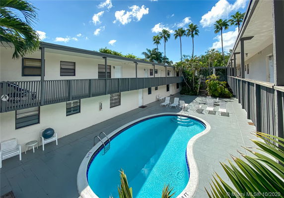Outdoor swimming pool surrounded by a two-story building.