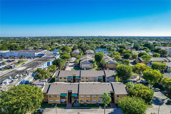 Aerial view of residential buildings surrounded by greenery and roads.