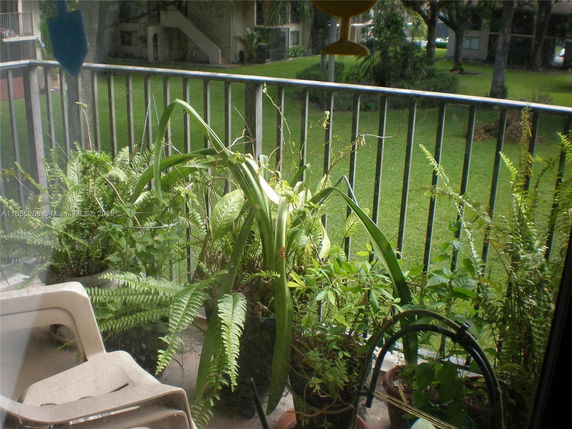 View from a building's balcony showing greenery and plants in the surrounding area.