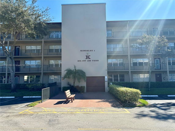 Front view of a multi-story residential building with balconies and a central entrance.