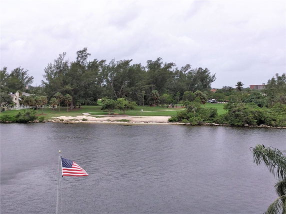 Panoramic view overlooking a body of water with a flag and trees in the distance.