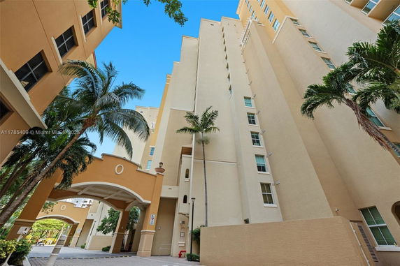 Front view of a multi-story building with arches and palm trees.