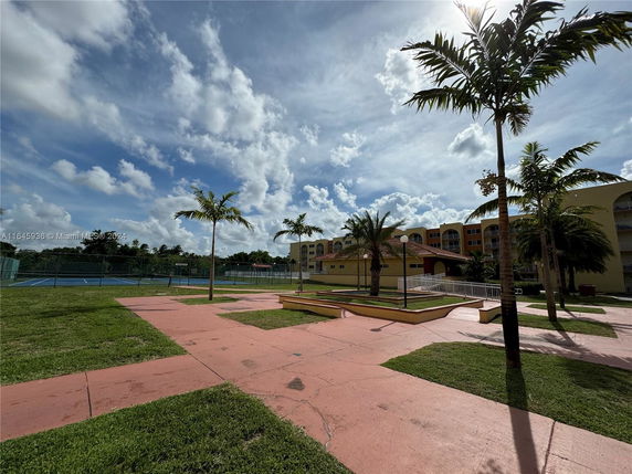 View of outdoor area with a tennis court and building in the background.