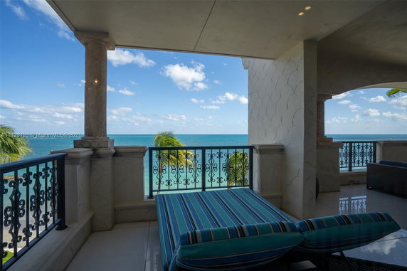 Seaside view from a balcony with ornate railing and lounge seating.