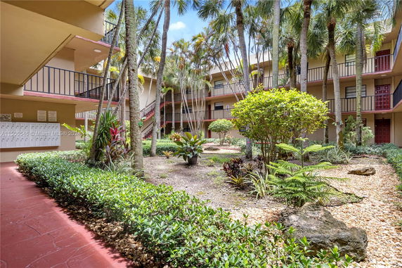 Apartment courtyard with lush landscaping and multiple stories of units.