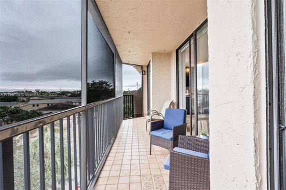 Outdoor balcony with seating and view of surrounding area.