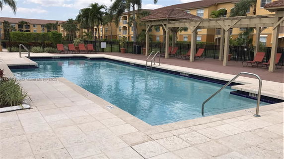 Outdoor swimming pool with lounge chairs and pergolas.