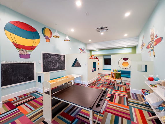Colorful indoor children's play area with wall murals and play equipment.