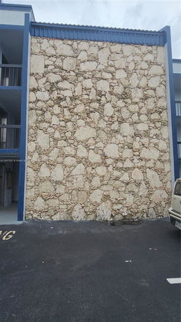 Stone exterior wall of a multi-story building with balcony railings visible.