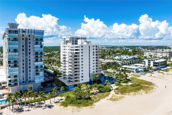 Aerial view of beachfront residences with multiple high-rise buildings and sandy beach.