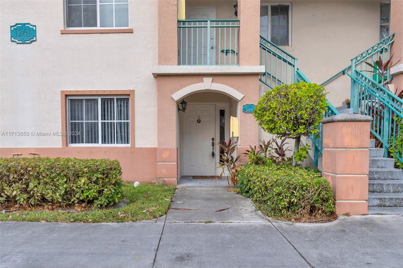 Front view of a multi-story residential building with a white door and peach accents.