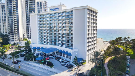 Front view of a multi-story hotel building with balconies and a blue canopy entrance.