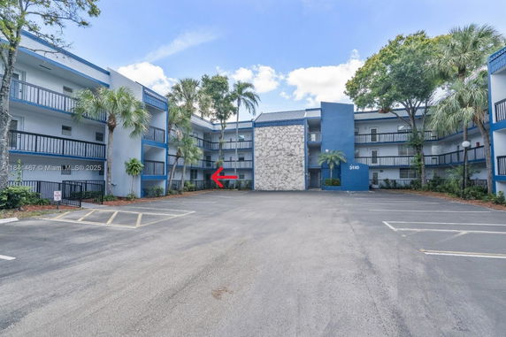 Front view of a multi-story apartment building with a central stone facade and blue accents.