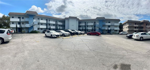 Outdoor parking area in front of a three-story apartment building.