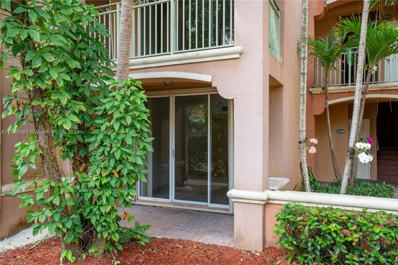 Front view of a building with a balcony and sliding glass door entry.
