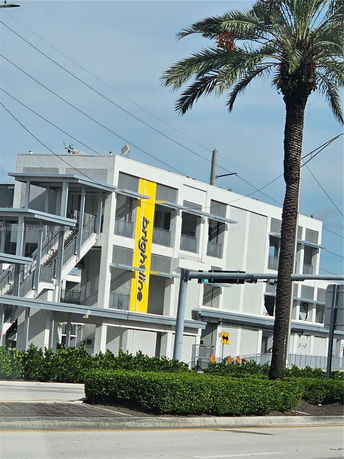 Front view of a modern multi-story building with a bold yellow vertical stripe and multiple balconies.