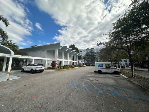 Outdoor parking area with a covered parking structure nearby.