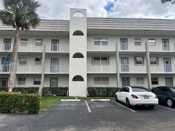 Parking area in front of a three-story residential building with balconies.