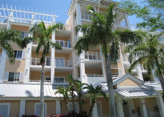Front view of a multi-story residential building with balconies and a metal roof.