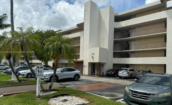 Parking area in front of a multi-story building with balconies.