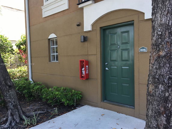 Front view of a building entrance with green door and small window.