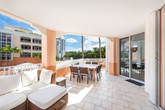 Outdoor patio area with white cushioned seating and dining table, view of adjacent residential buildings.