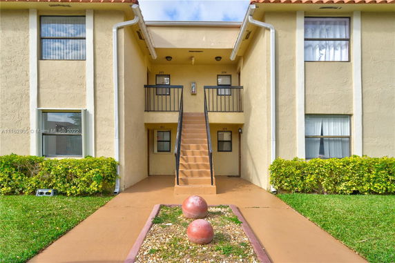 Front view of a two-story building with external staircase and multiple entrances.