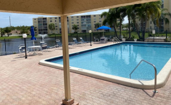 Outdoor swimming pool area with lounge chairs and umbrellas.