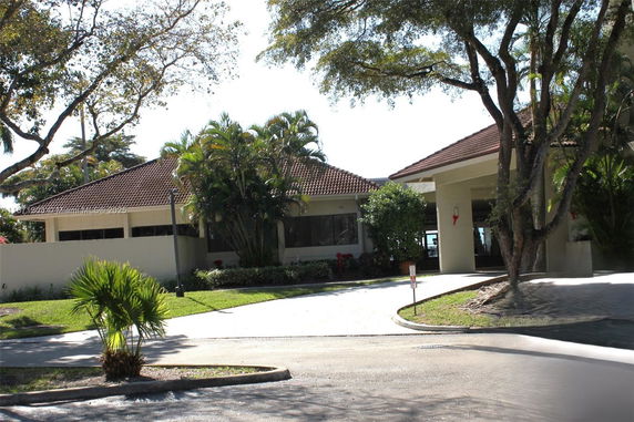 Front view of a house with a tiled roof and surrounding greenery.