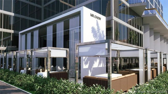 Front view of a modern building with glass facades and outdoor seating areas.