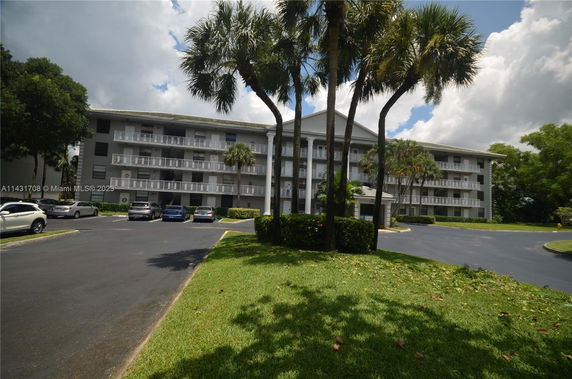Front view of a multi-story residential building with balconies and a parking area.