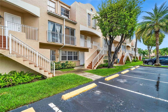 Front view of residential building with multiple entrances and adjacent parking spaces.