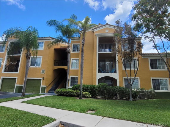 Front view of a multi-story apartment building with balconies and garage doors.